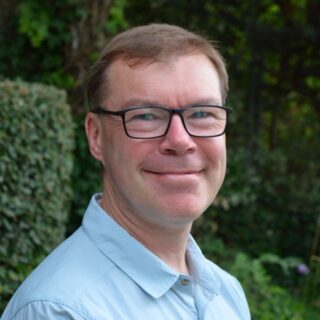 CAP trustee, Julian, wearing a blue shirt and glasses, smiling at the camera