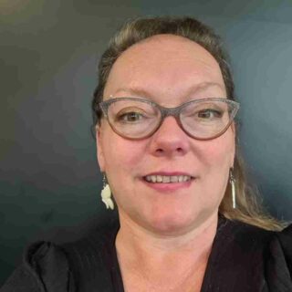 Helen Ganney, a white lady with short brown hair and colourful, quirky glasses.