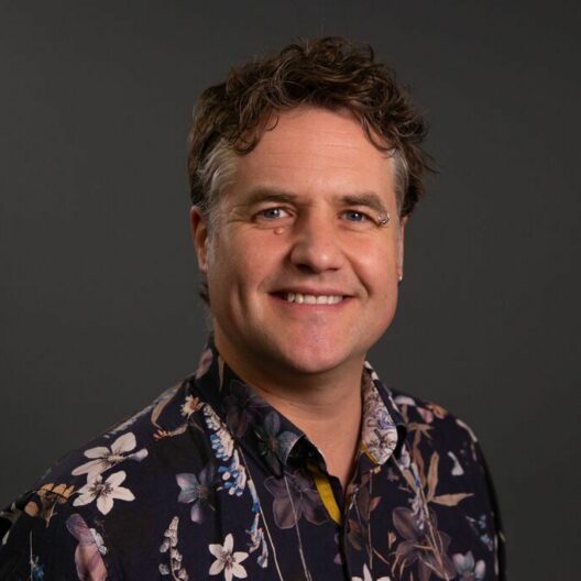 Alex Jones, CAP's Director of Fundraising, a while male with short curly hair and a flowery shirt.
