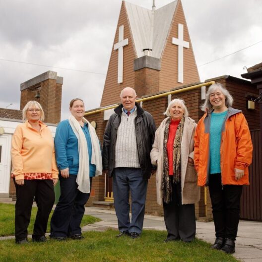 Five people stood outside their local church, smiling at the camera