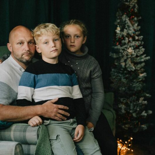 A CAP client sat on the sofa with his two children at Christmas, looking into the camera