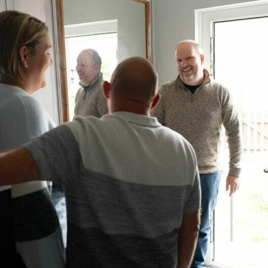 Two CAP clients opening their front door to their debt centre manager visiting their home