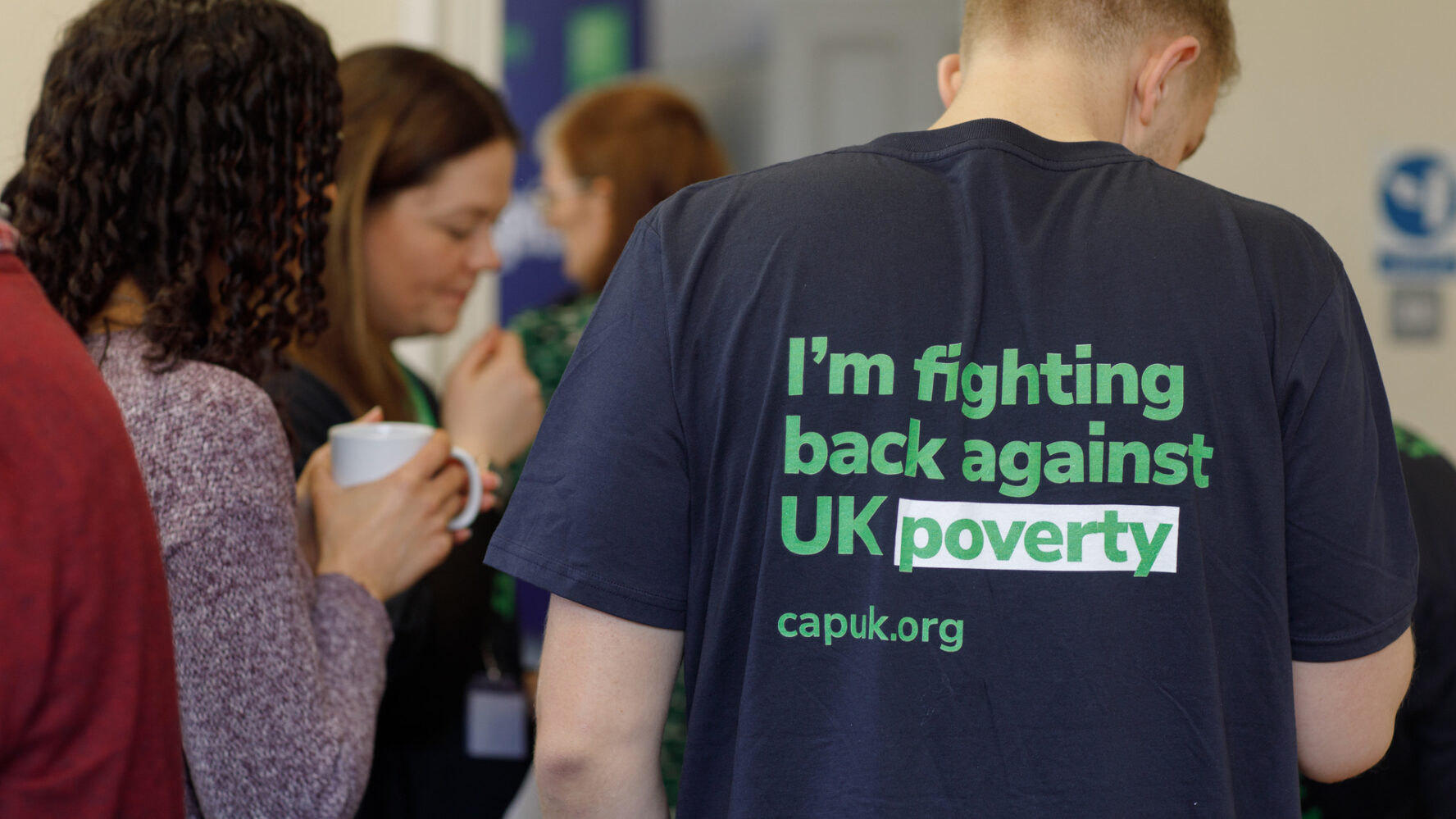 A man at an event wearing a Christian's Against Poverty T-shirt