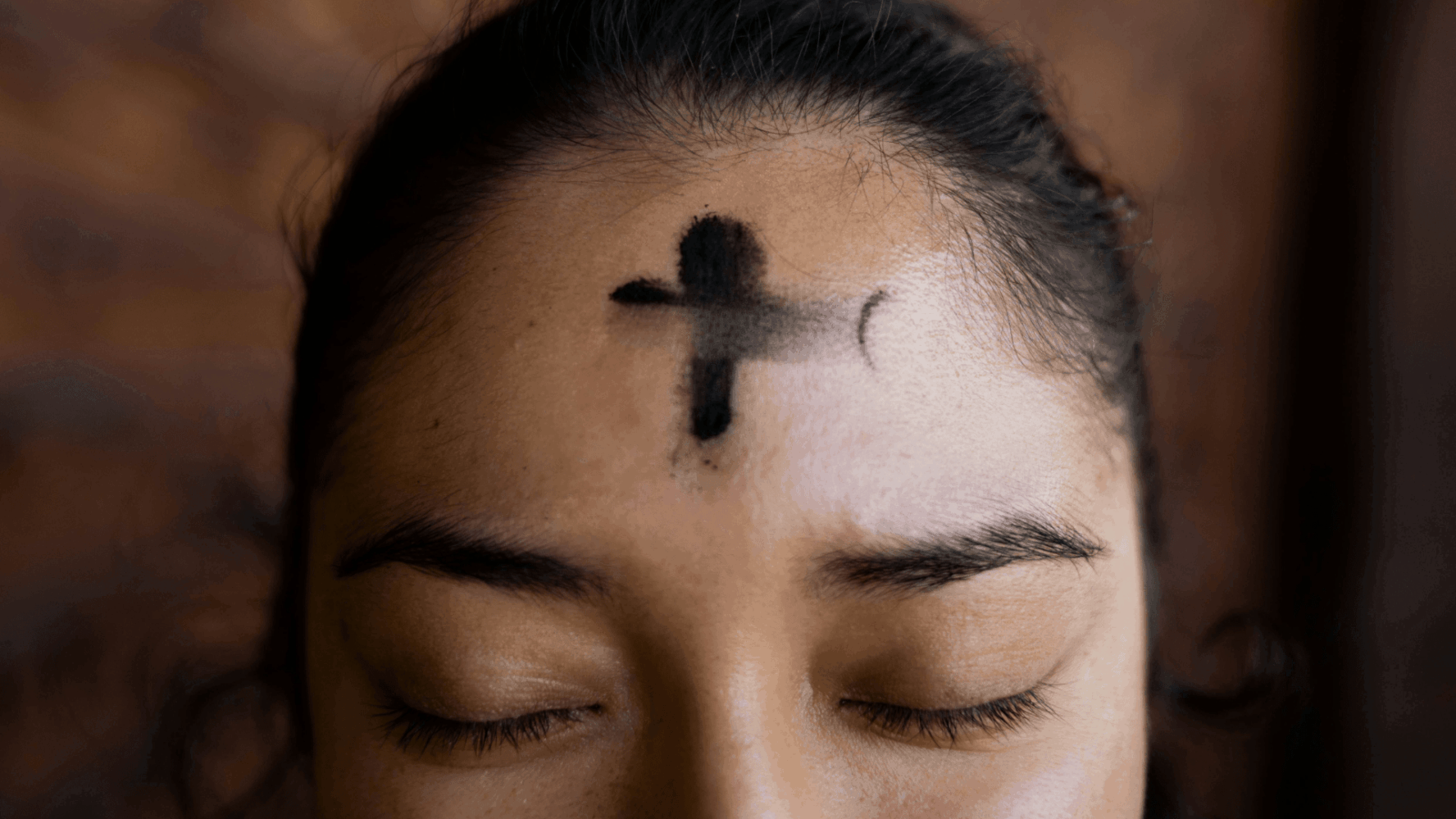 A woman with ash placed in the shape of a cross on her forehead. Photography by Annika Gordon.
