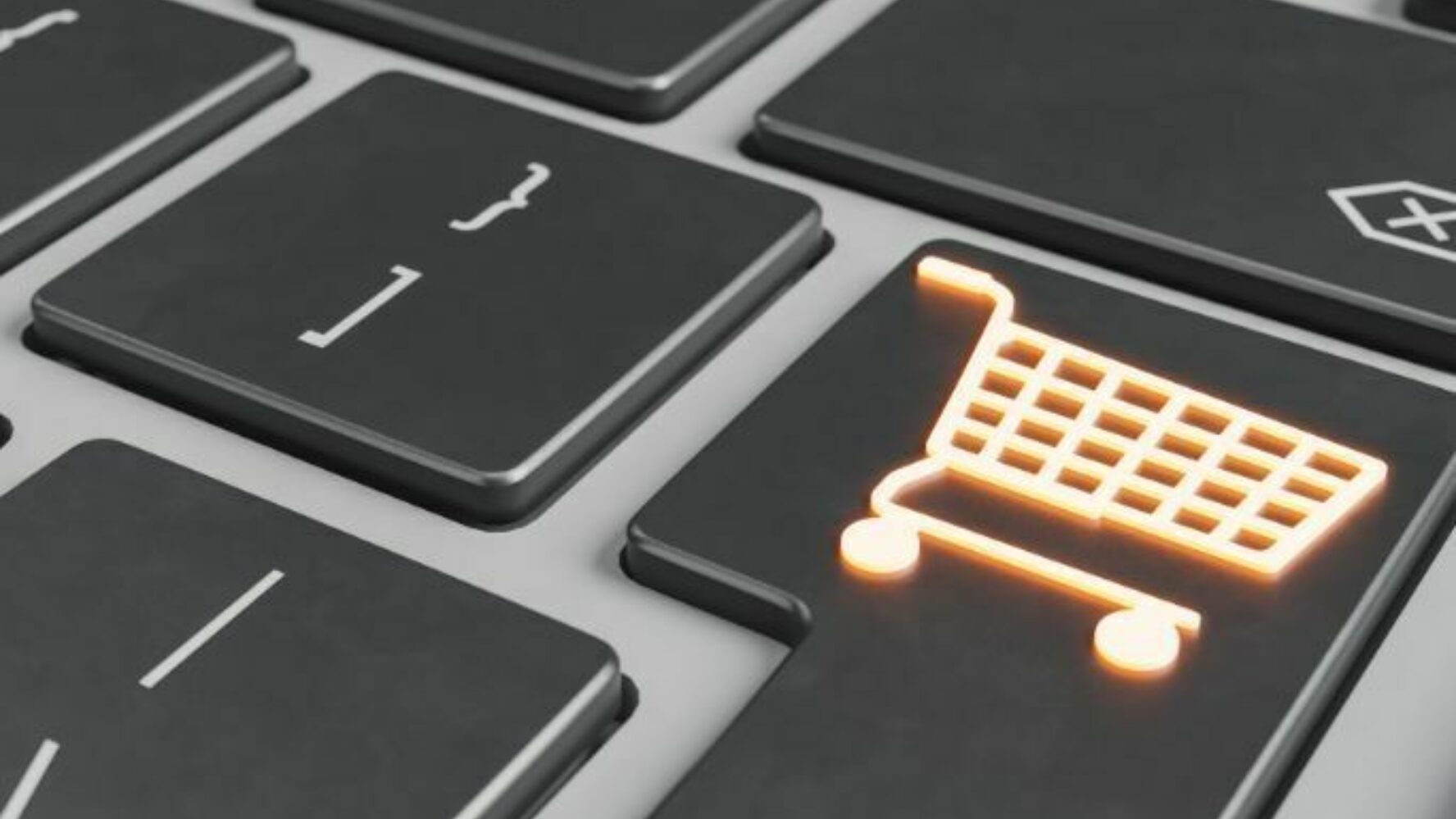 A zoomed in photo of a computer keyboard. On the 'enter' key is a lit up shopping trolley symbol.