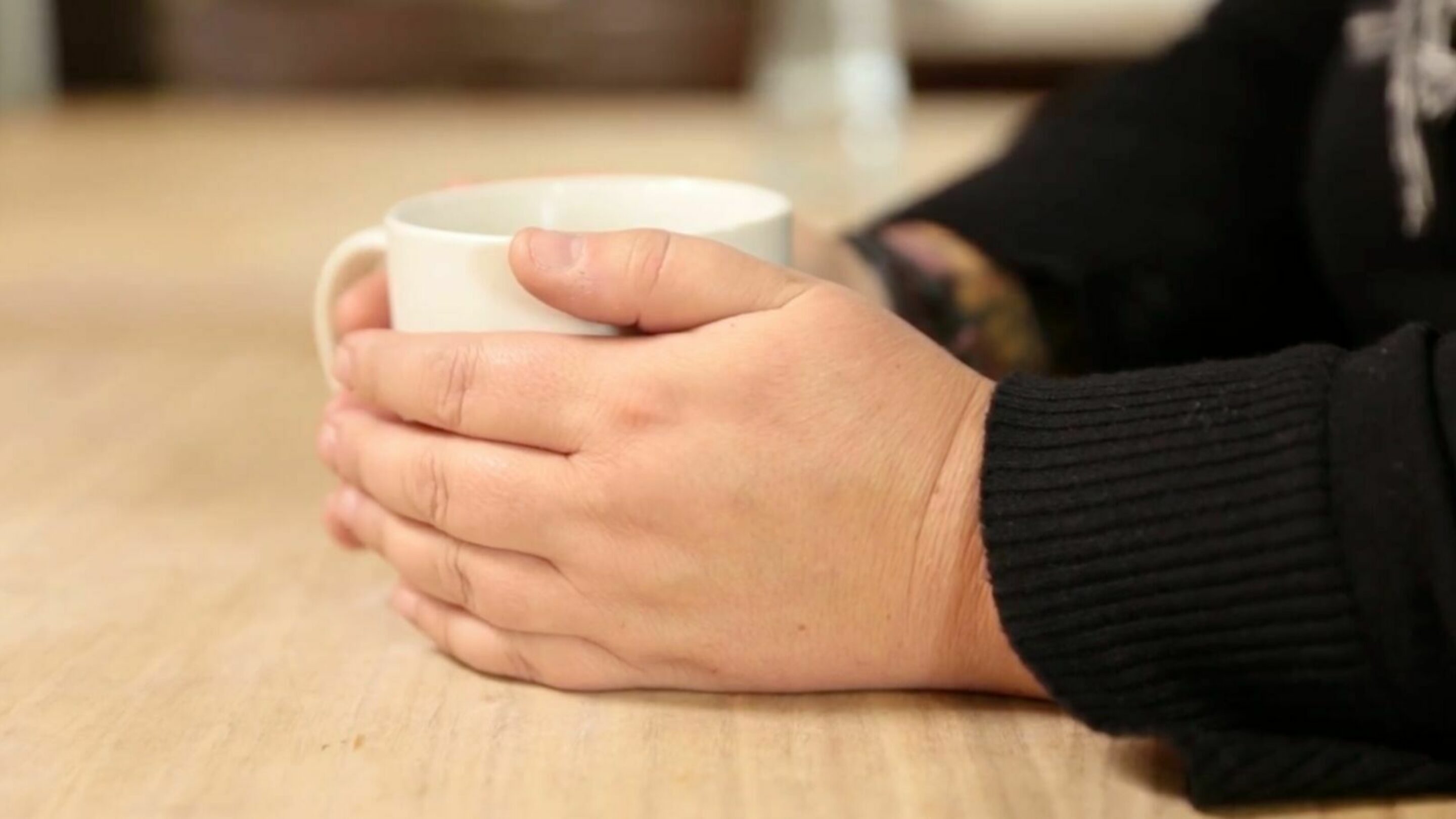 A person hands holding a mug, from the side