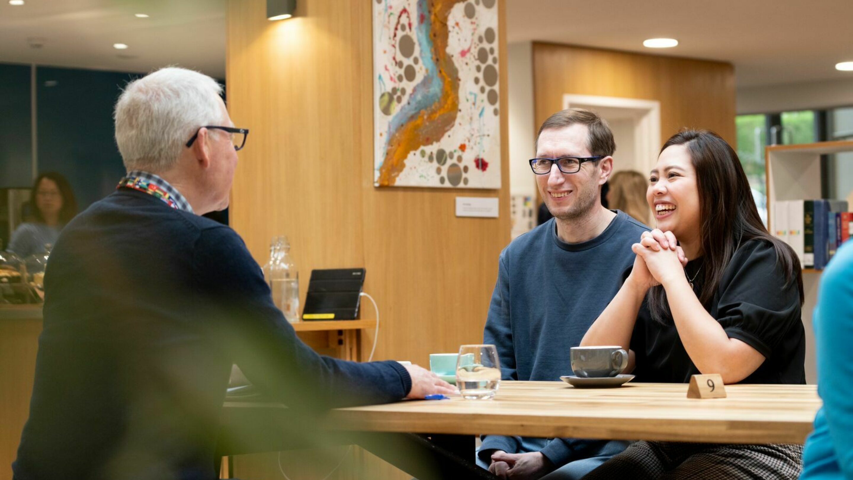 Young couple, Tim and Sue, sat at a coffee shop table with their Job Club Coach, Nick