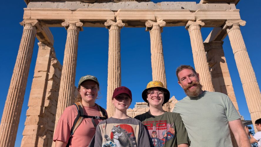 CAP supporter Jim, a while male with brown hair and a beard, standing in front of some Roman ruins, with his wife and two daughters