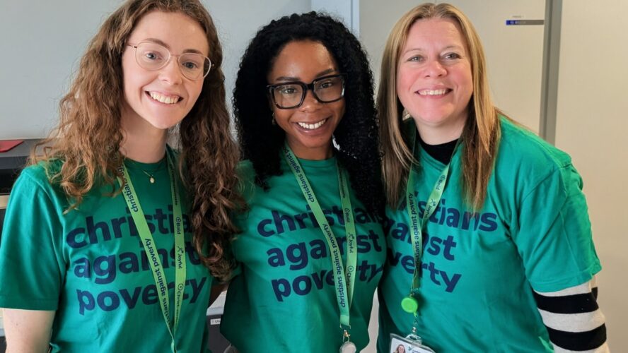 Three CAP employees wearing green Christians Against Poverty t-shirts, smiling at the camera