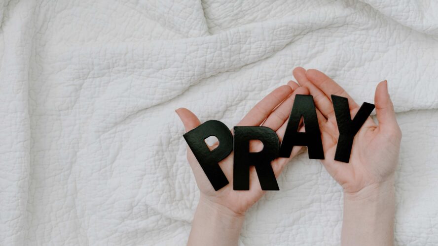 Hands held open with letters spelling pray.