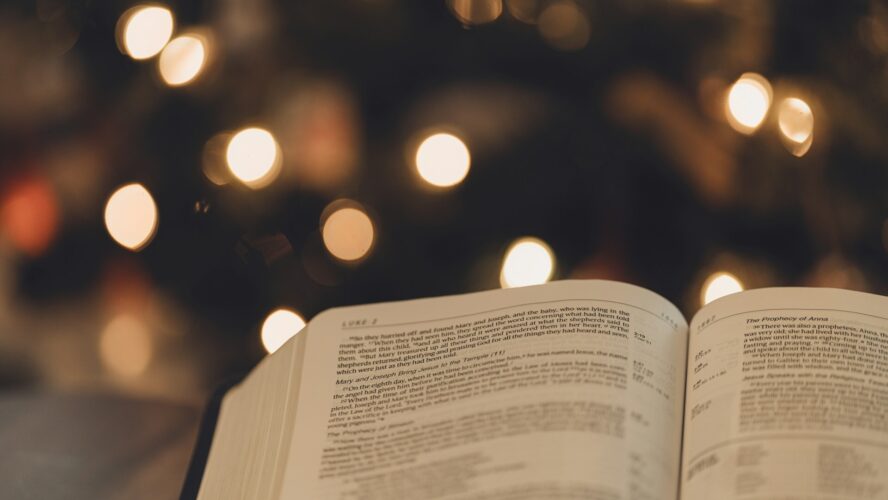 Open bible with Christmas tree and lights in the background