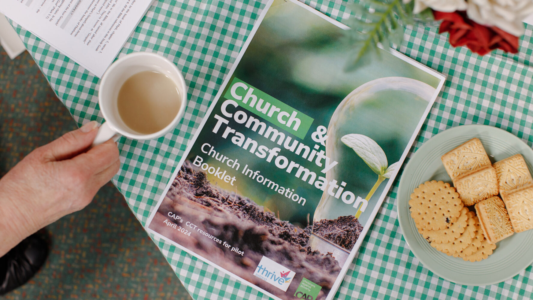 Birds-eye photo of a table with a CAP leaflet that reads 'Church and Community Transformation - Church Information Booklet'