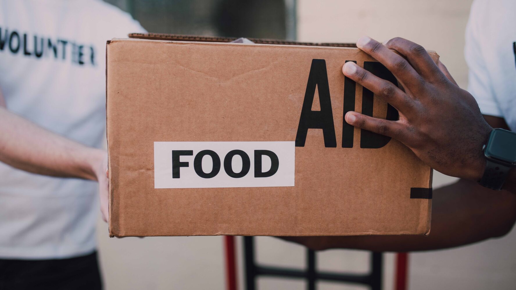 Hands holding a cardboard box labelled food aid