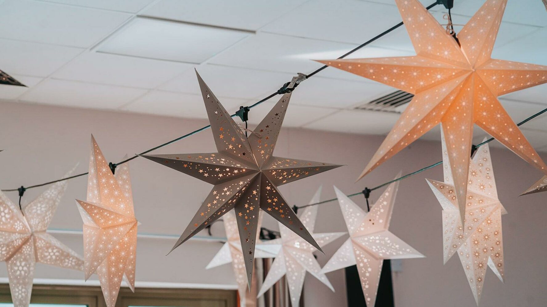 White, grey and gold star lights, hanging across the ceiling of a town hall. Photo by Matthew Leung (Tsz Lok Photos).