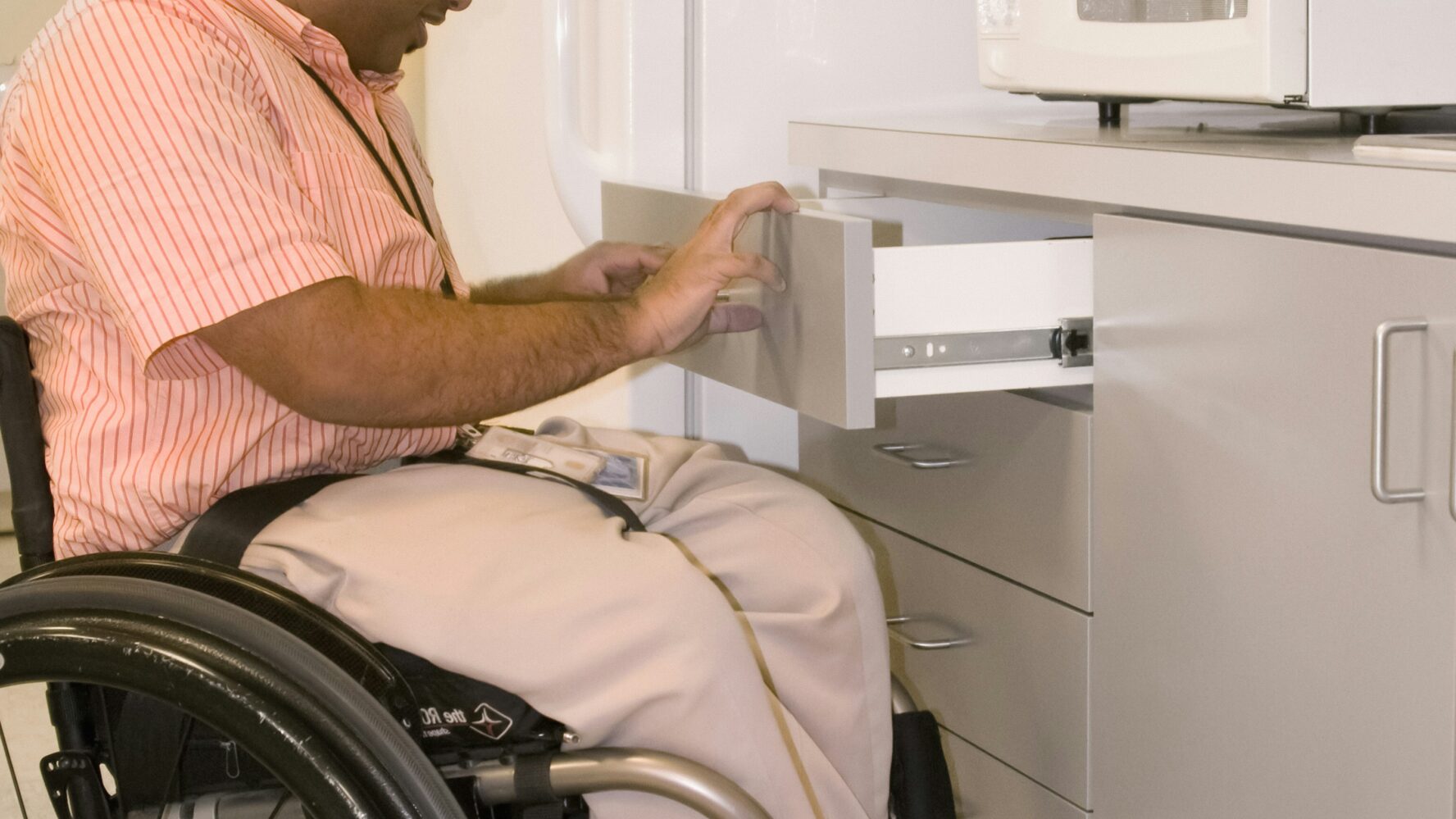 man in wheelchair opening a kitchen drawer