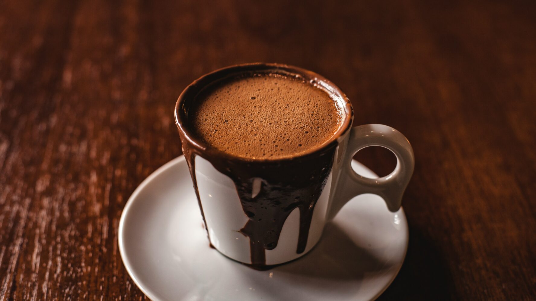 A hot chocolate in a mug, with chocolate dripping down from the side of the mug