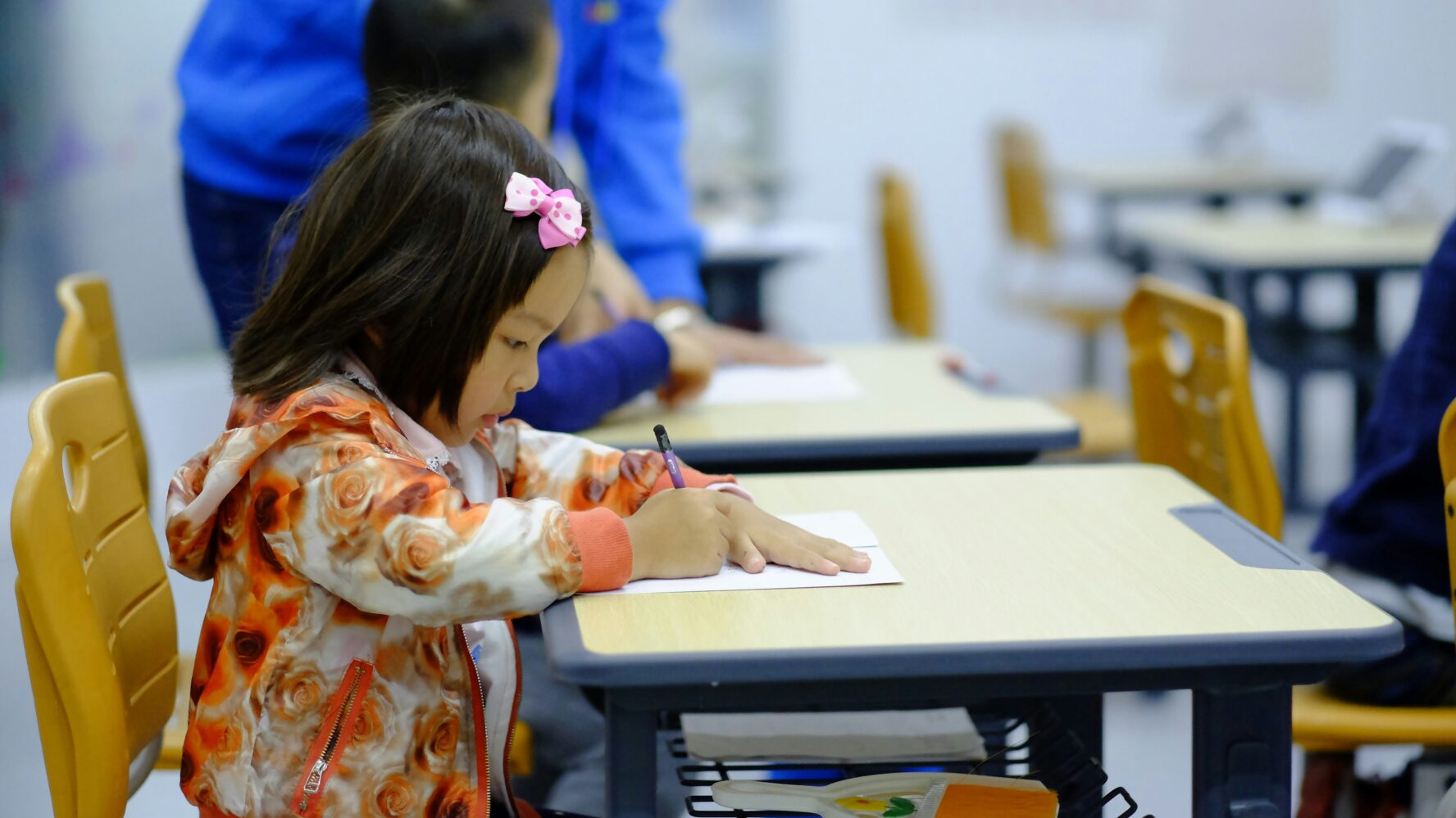 A smaller child sat at a school desk, writing