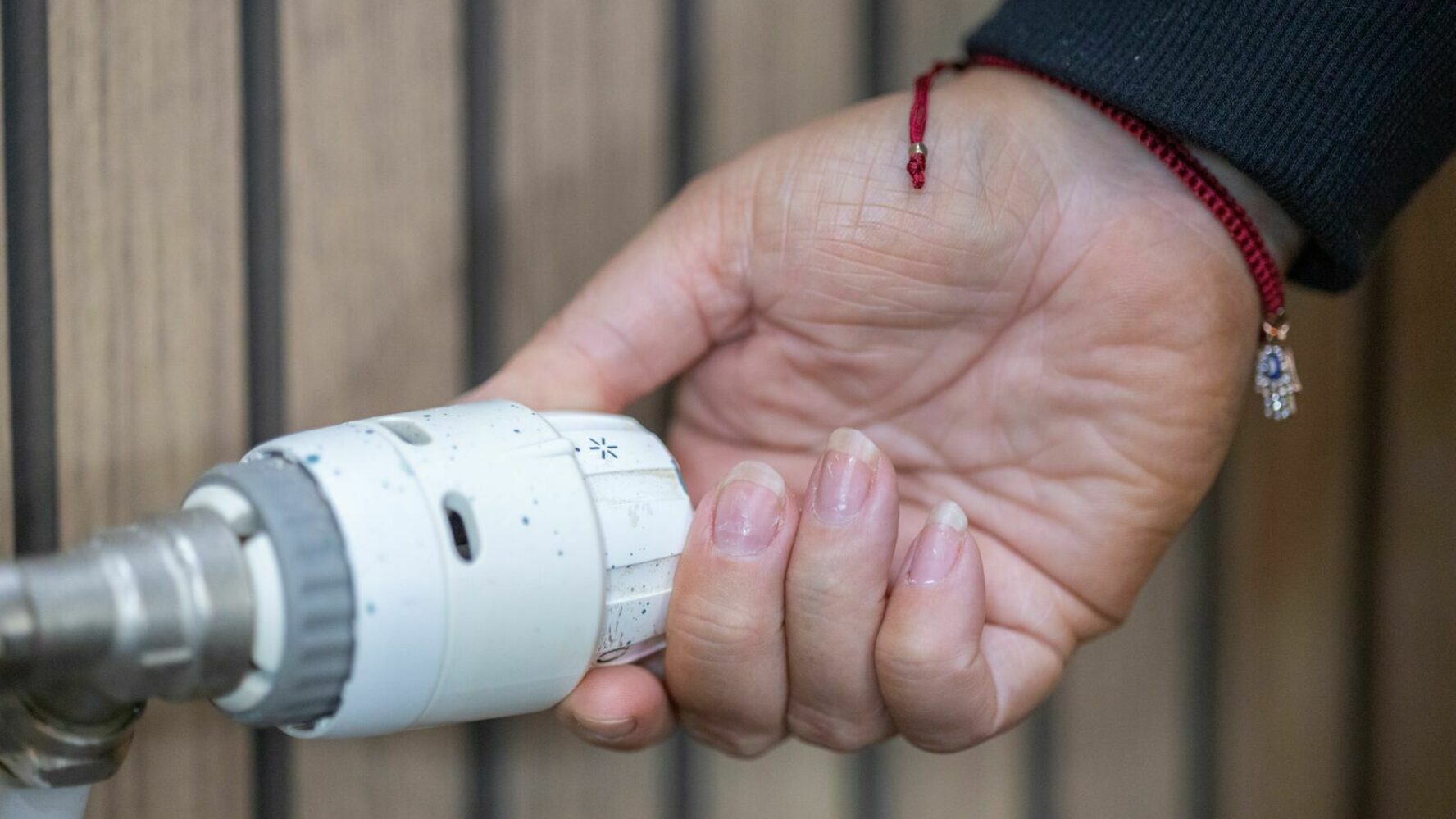 Person's hand turning a radiator dial