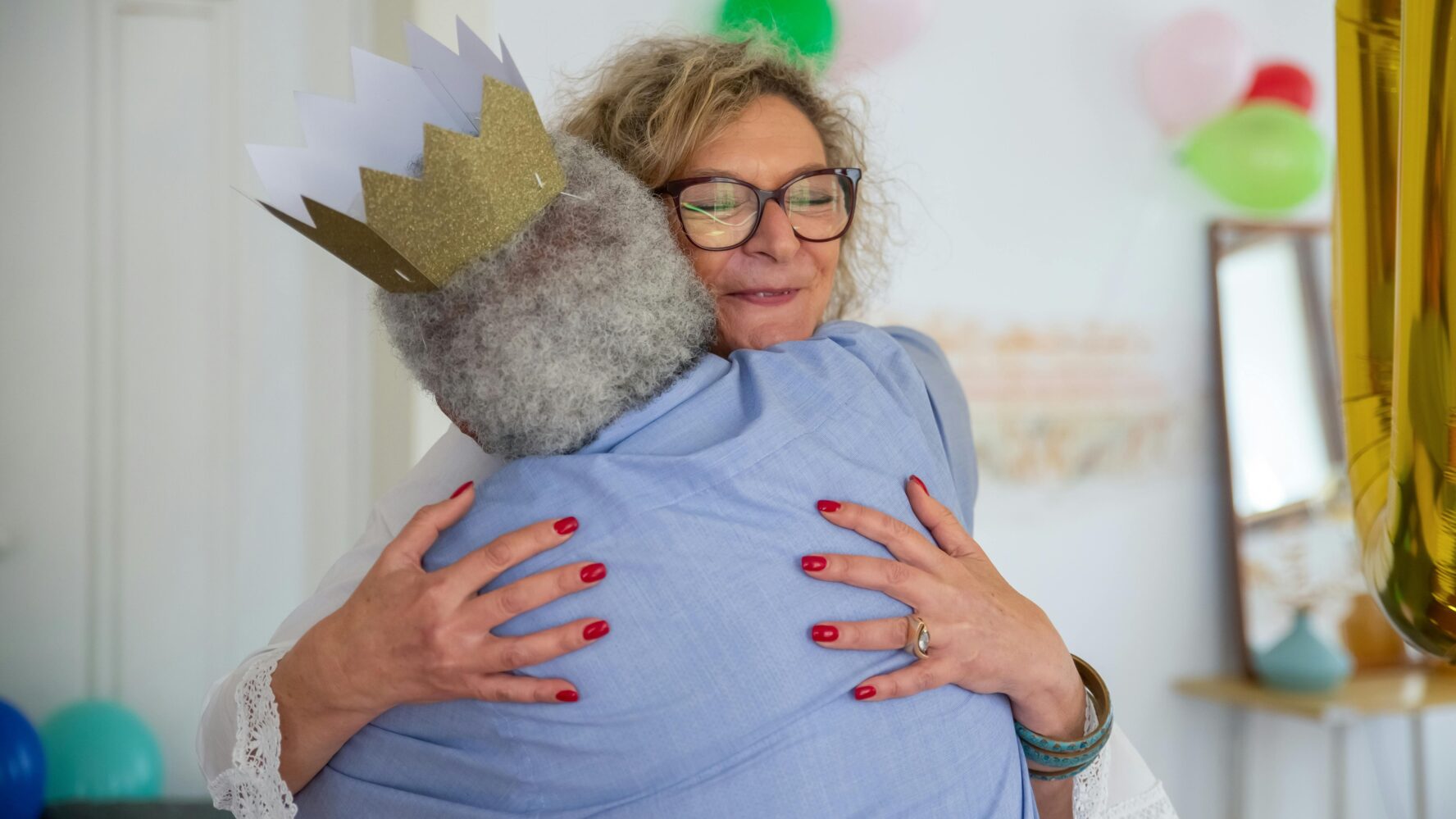 Image of a middle aged woman hugging an older woman tightly and smiling