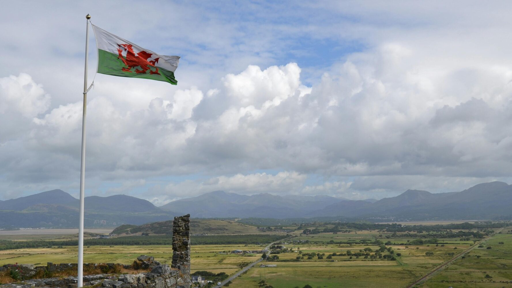 A Welsh castle overlooking a town, with the Welsh flag flying