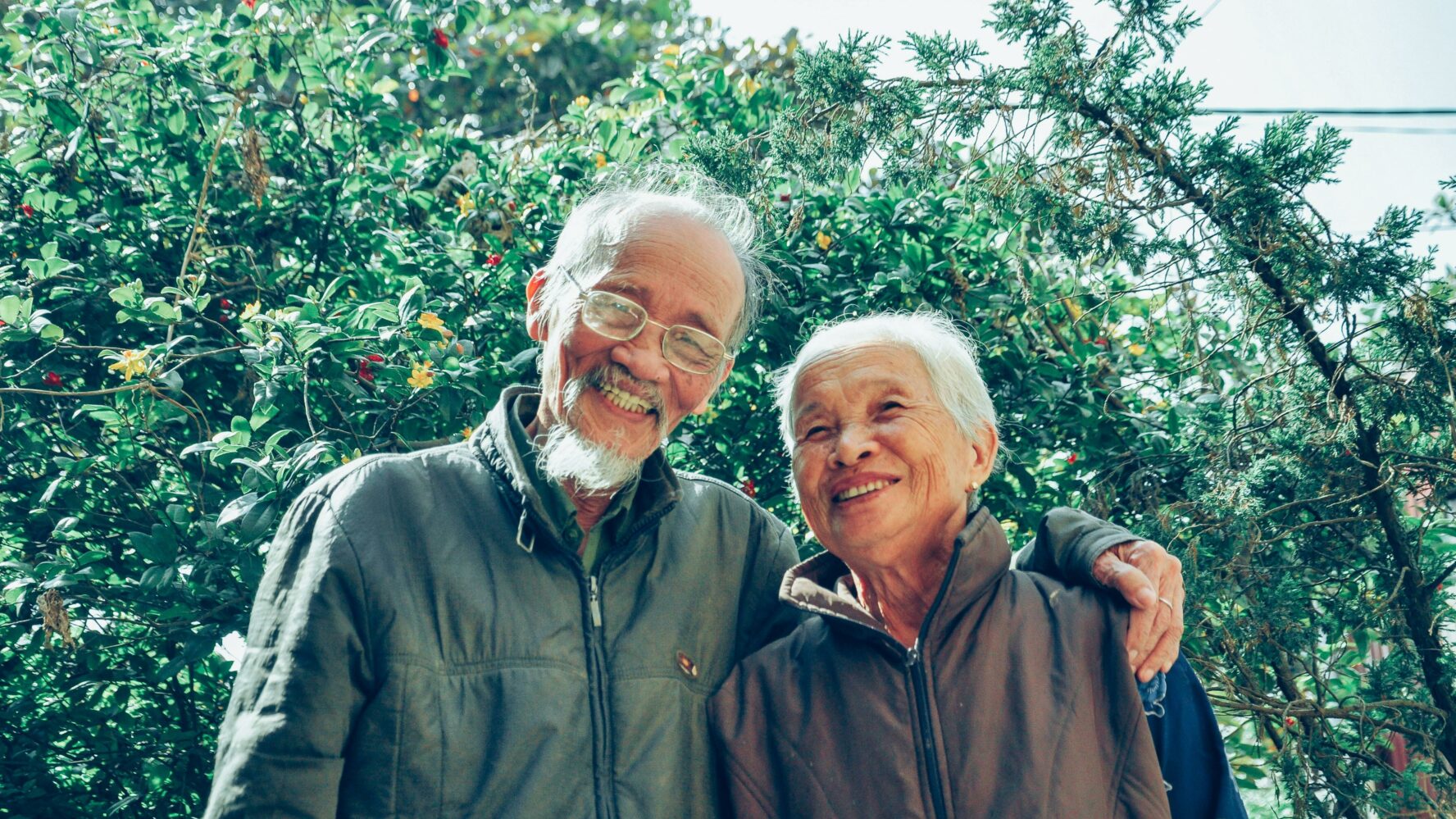 An older couple. Both of them are smiling at the camera.