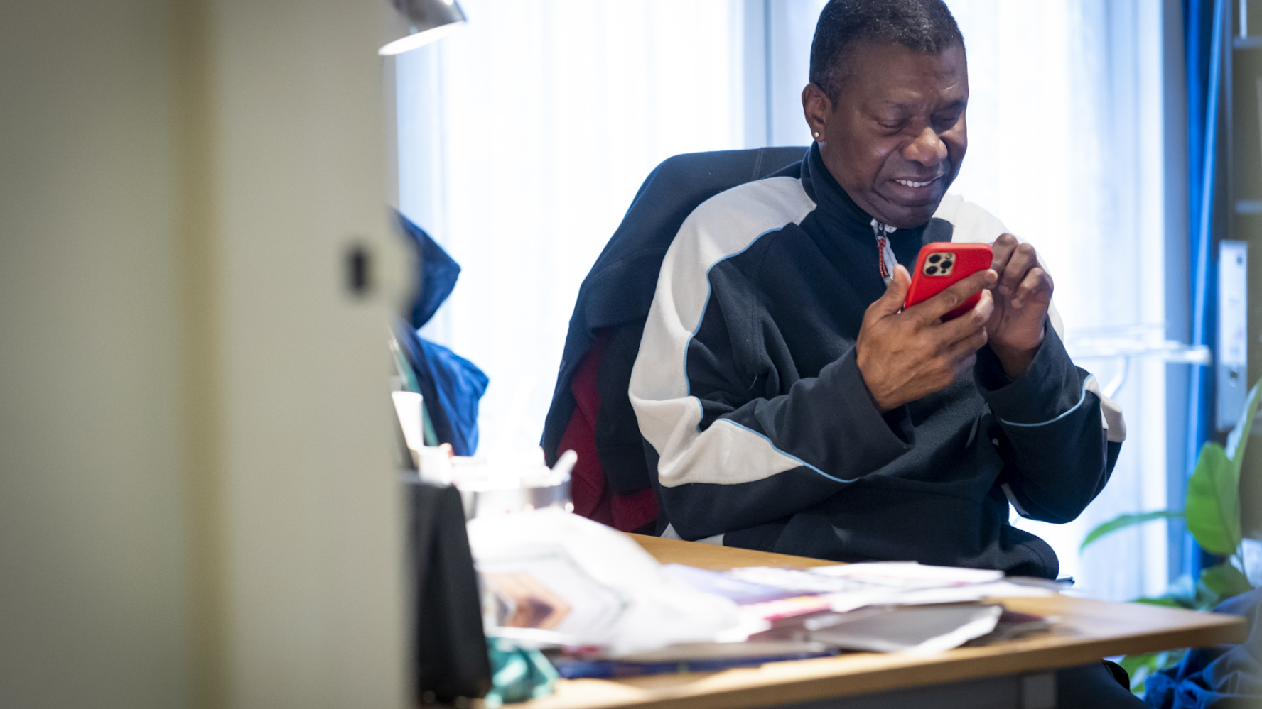 Man sat in his home, smiling at his phone