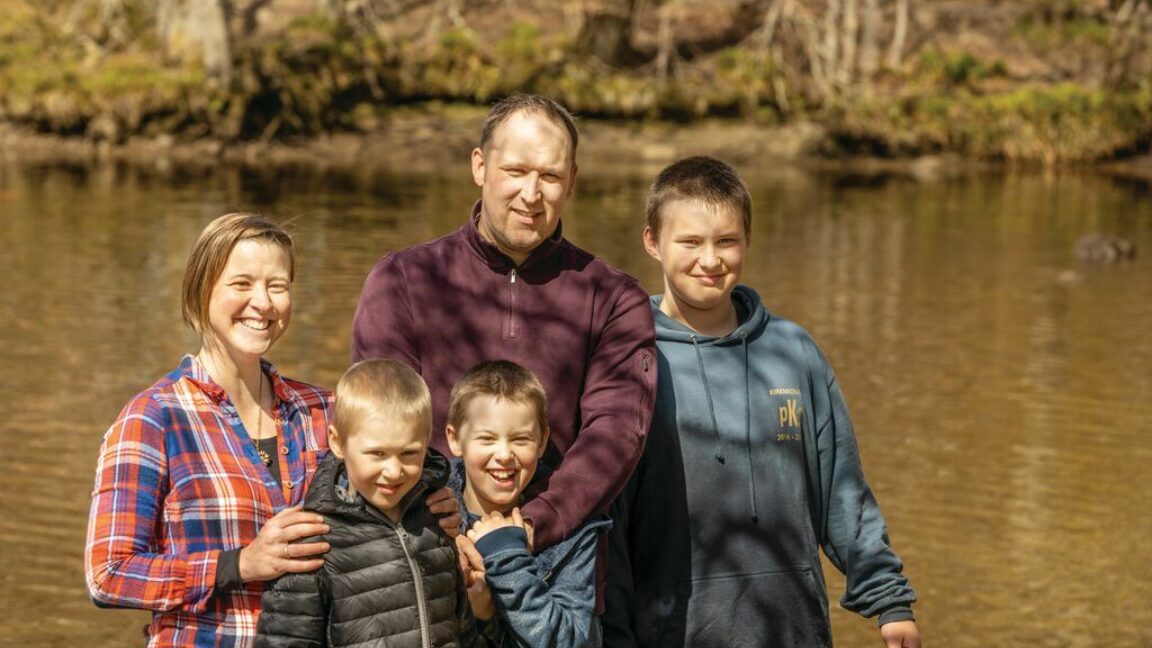 Jenny and her husband Steve, and their three boys, all stood in front of a lake and smiling at the camera. This family became debt free through CAP and are now able to build a legacy for their future.