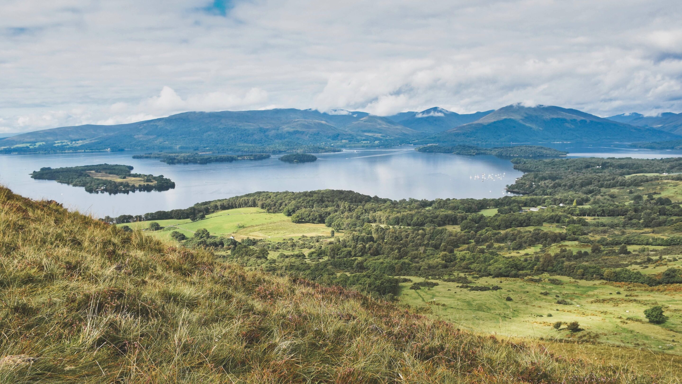 Lake and hills with a blue sky and clouds.