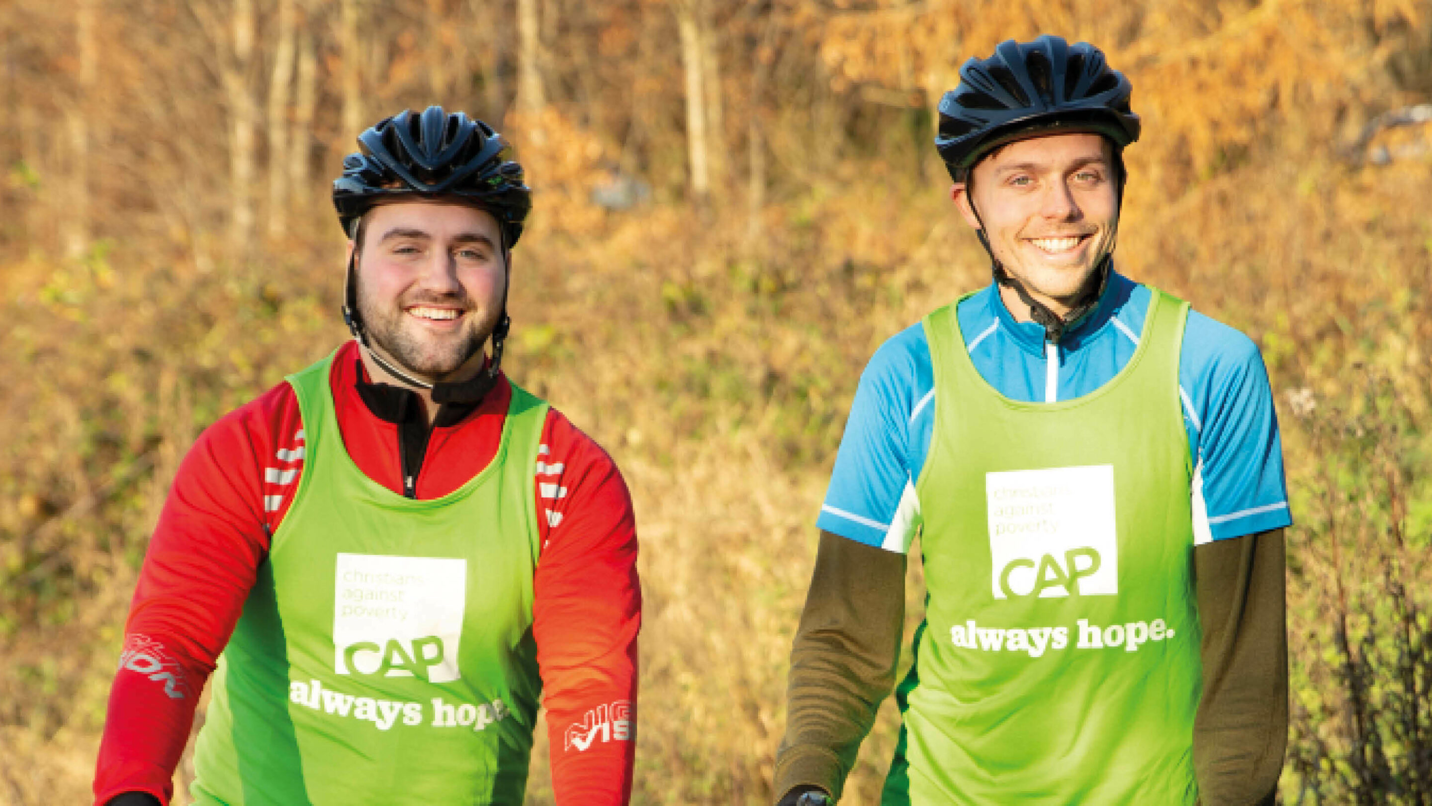 Two male CAP fundraisers wearing bike helmets taking part in a sponsored bike ride.