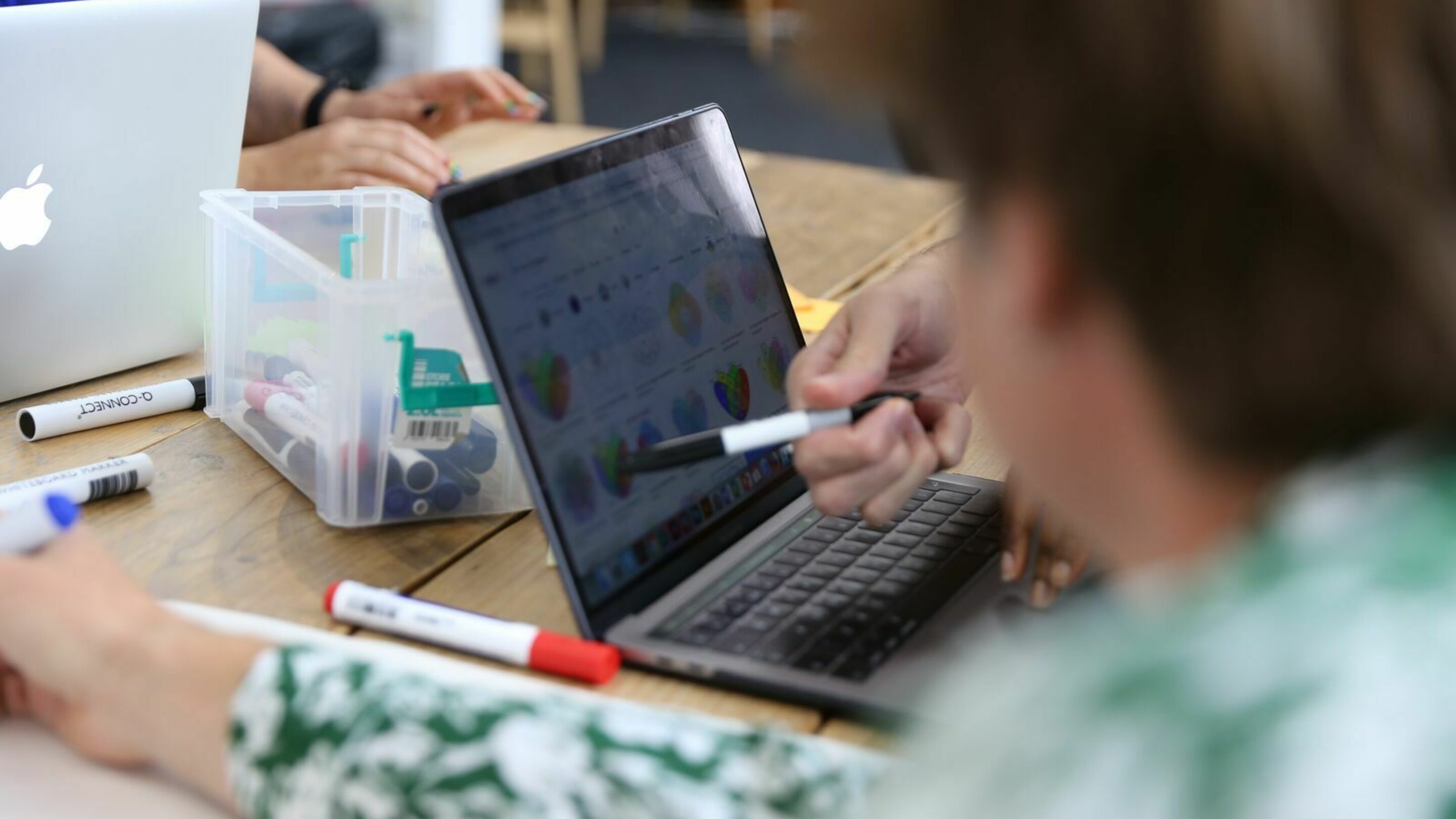 Two people looking at a laptop and pointing at it