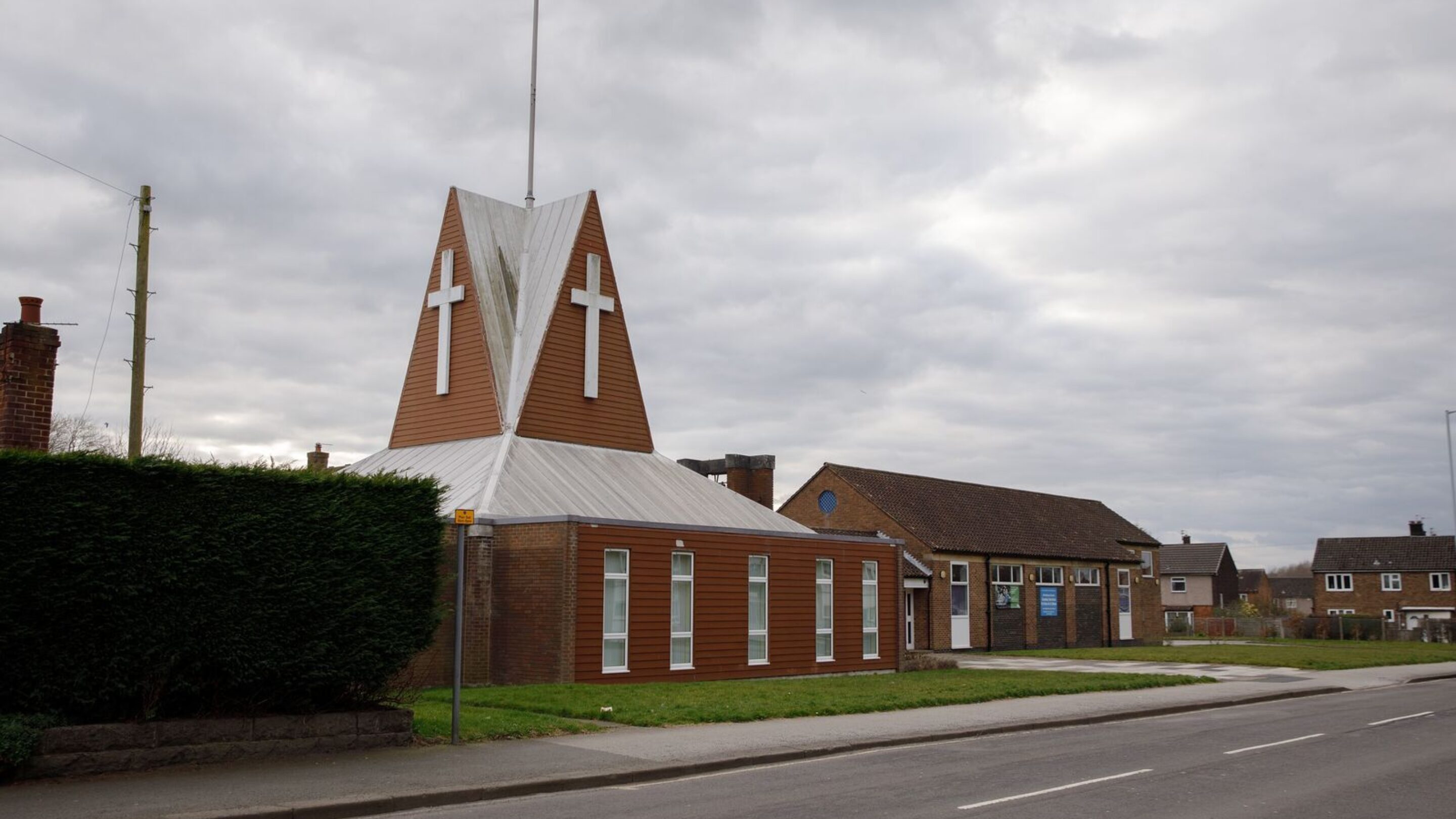 Photo of the outside of a UK parish church, with a white cross on the top