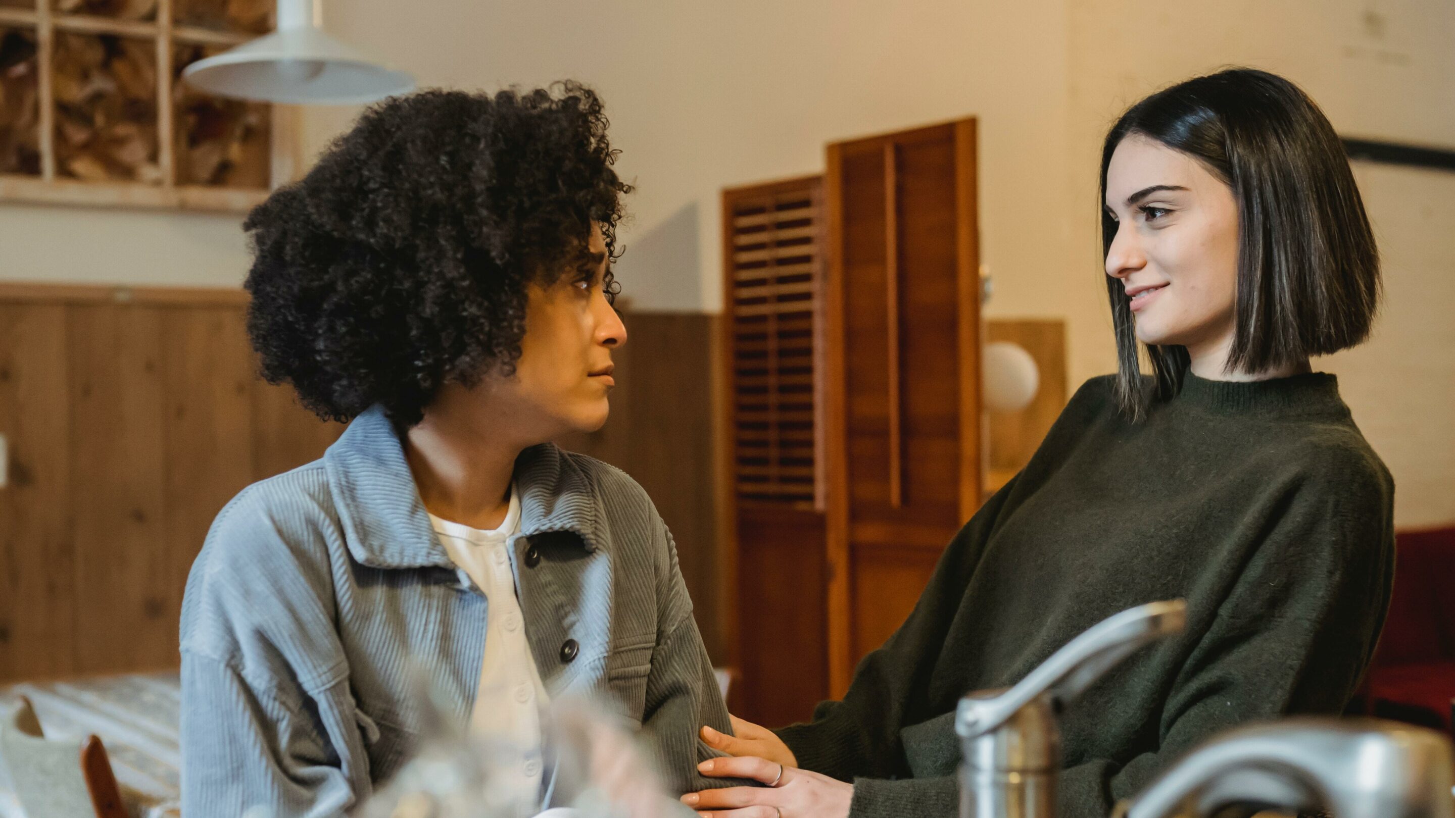 Two female friends, one is comforting the other by holding her arm and looking supportive.