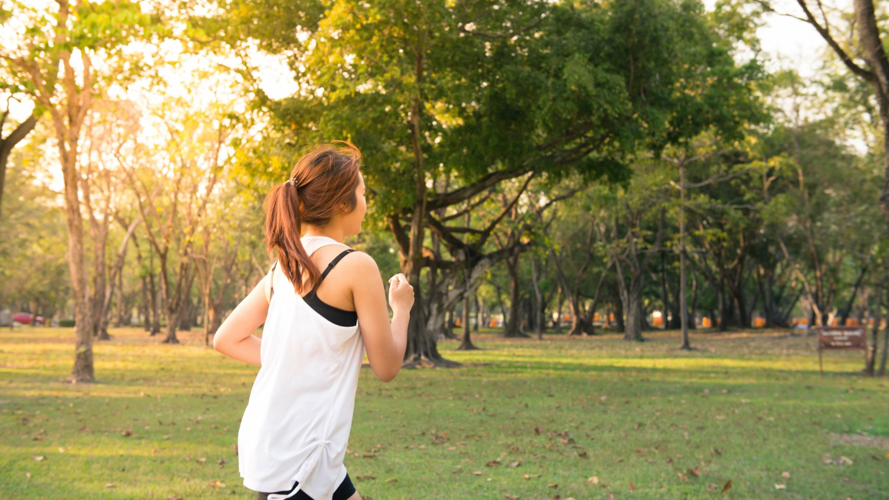 A young woman running by herself in public garden space.