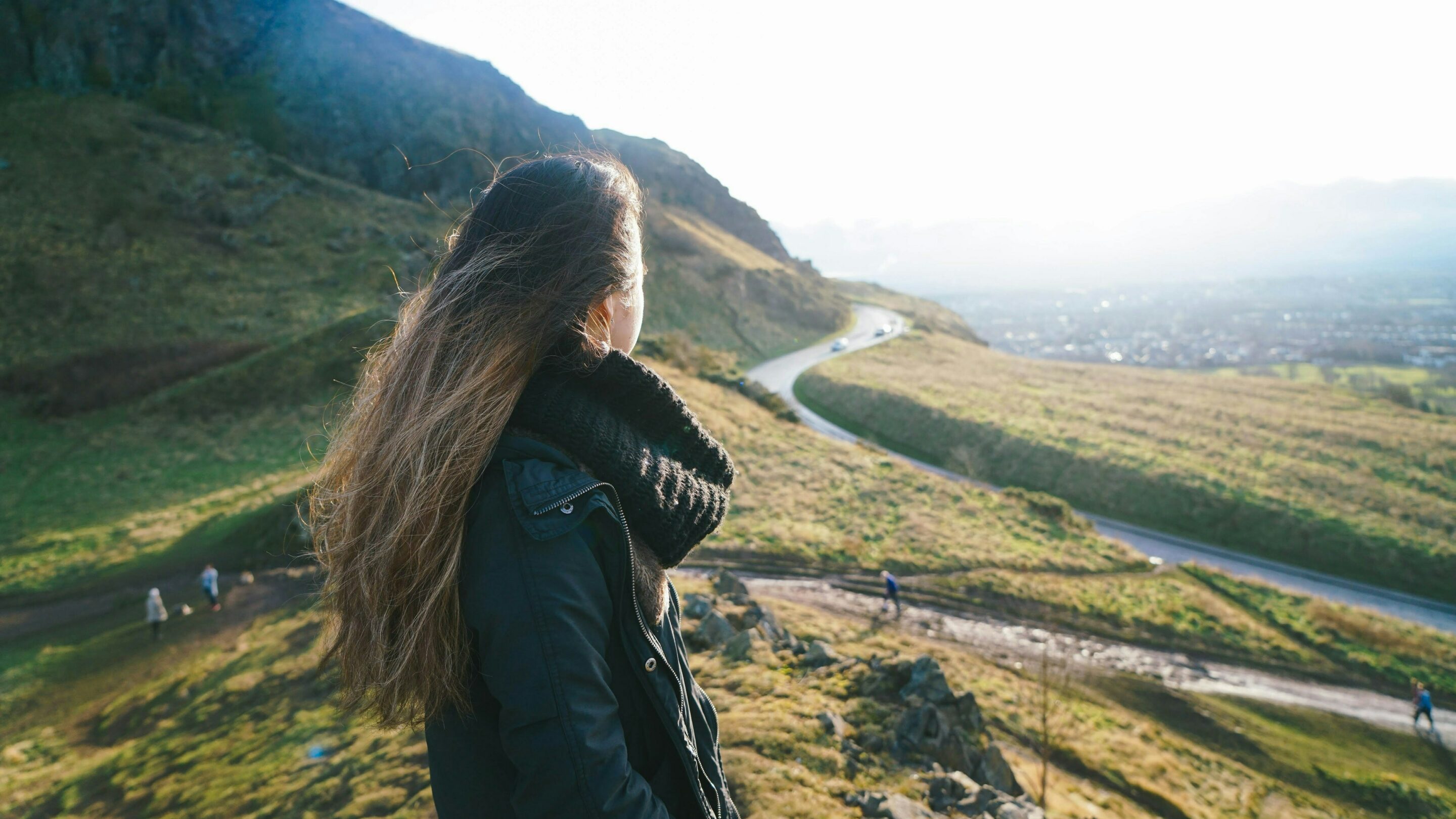 Woman stood at the top of a hill looking out at the green landscape