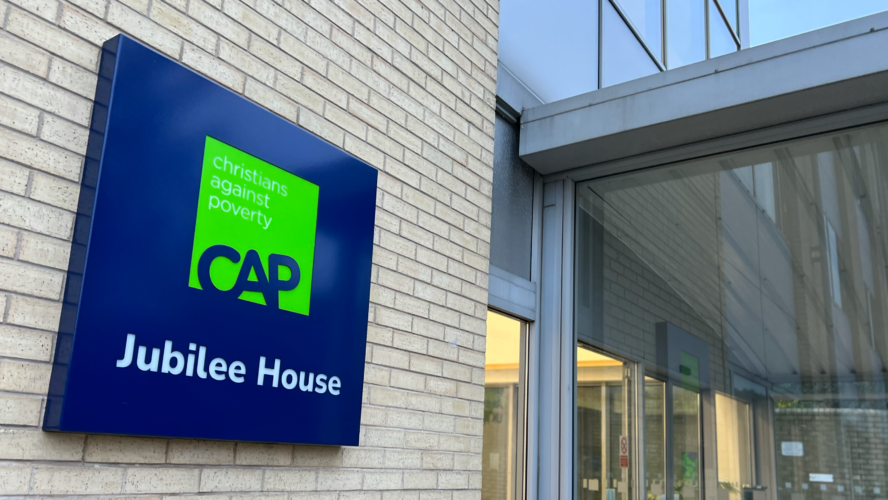 The front of CAP's support hub building in Bradford, a close up shot of CAP's green logo on a blue sign.