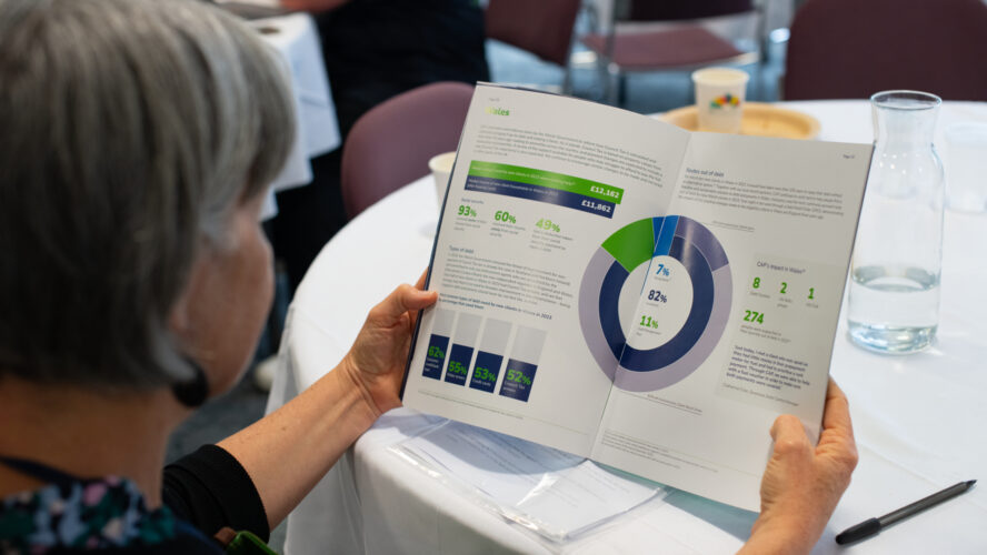A lady sat at a table, reading a report containing statistics and charts