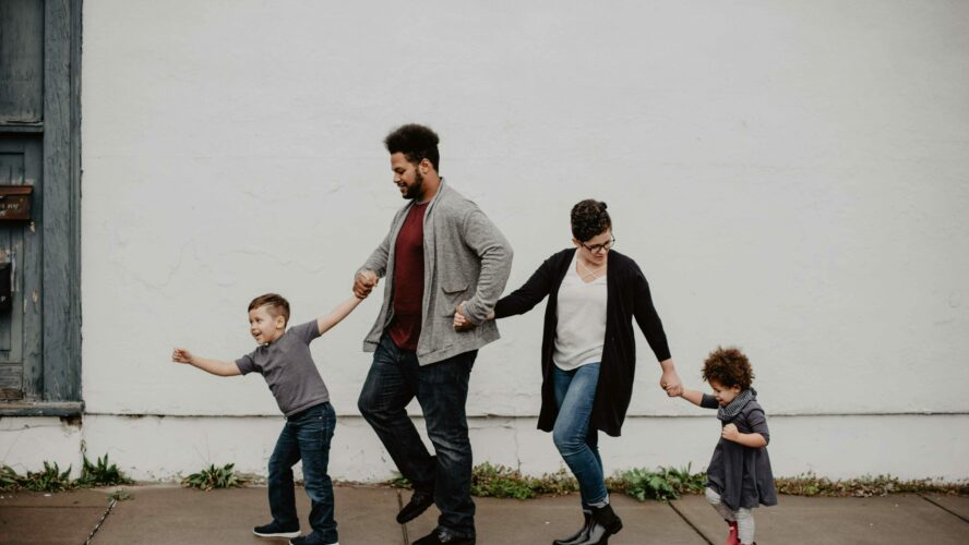 Young family walking down the street together, laughing.