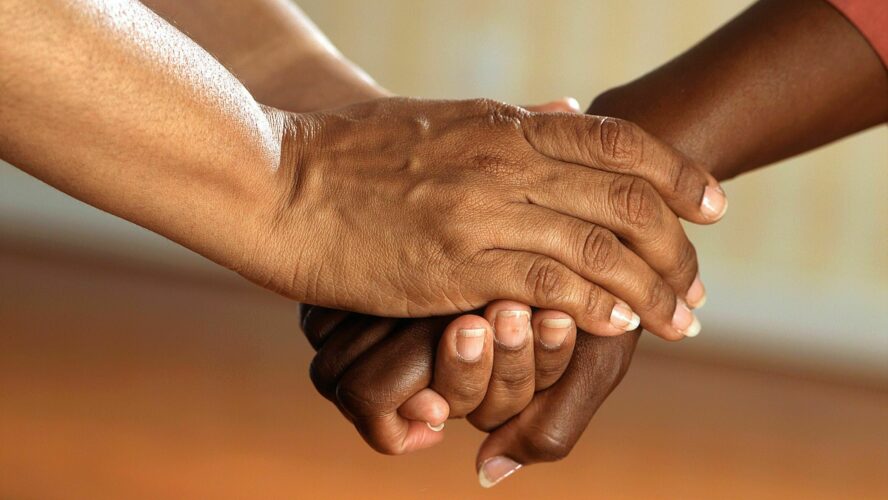 Two individuals holding each others hands in support.