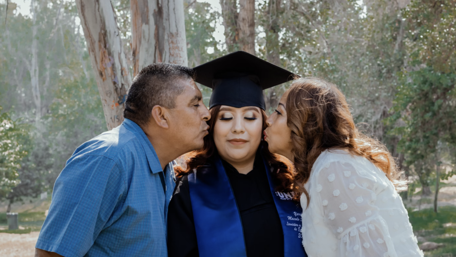 A university graduate stood in between parents on her graduation day.