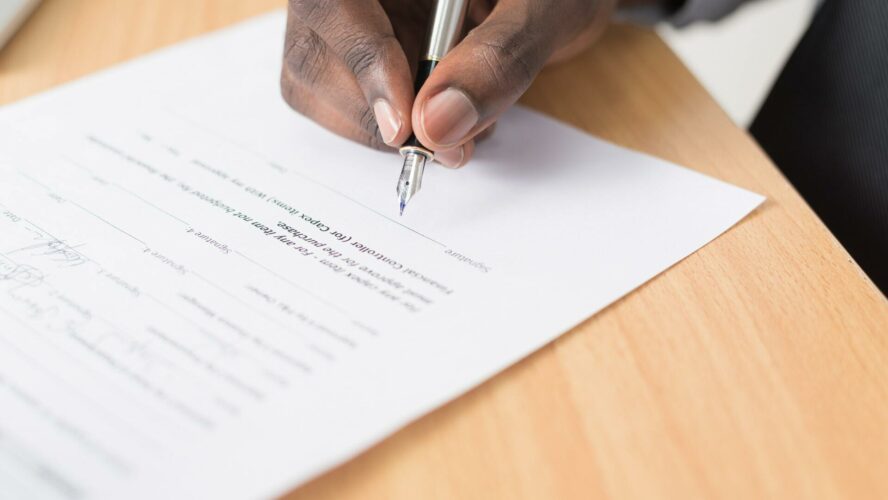 Male hand holding a fountain pen, signing a document.