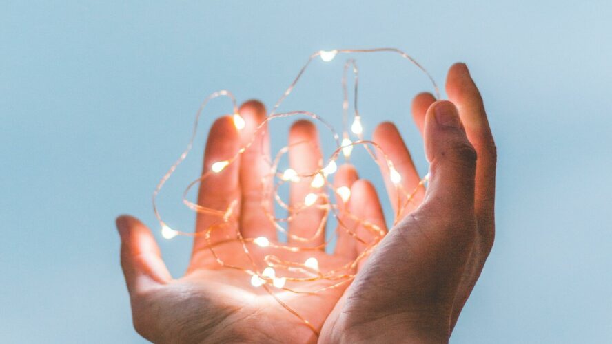 Hands of a person struggling to pay energy bills holding fairy lights.