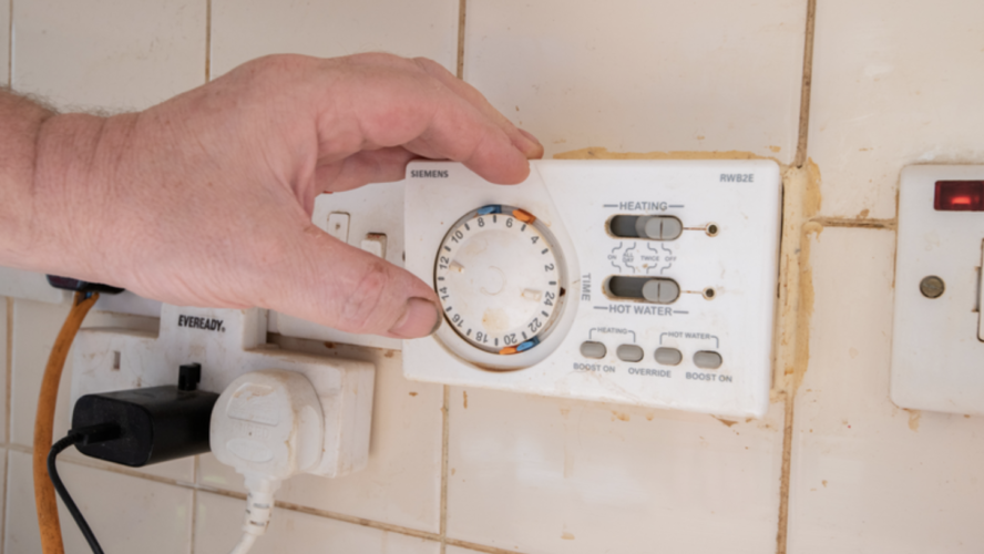 Person's hand on a thermostat at home