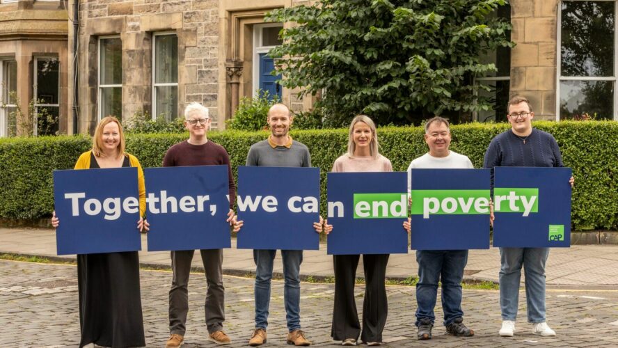 6 people standing in a line, holding signs that together read 'Together, we can end poverty'