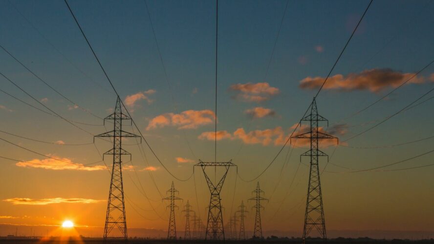 Group of pylons going into the distance, silhouetted at sunset.