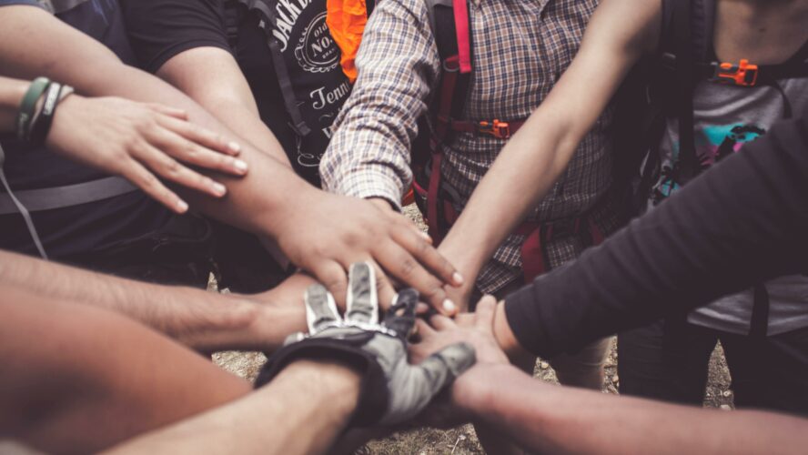 People placing their hands on top of each other in a circle.