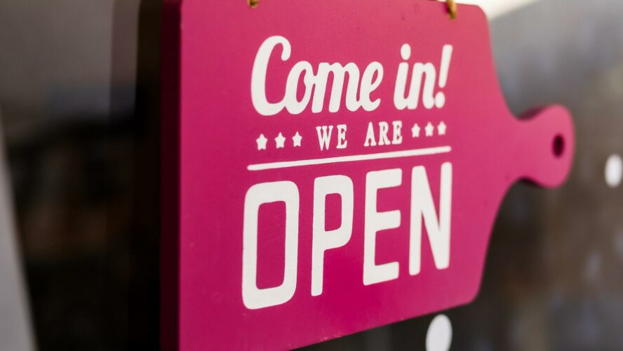A bright pink sign reads 'come in, we're open'