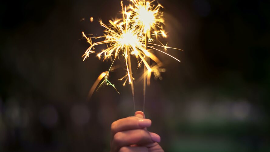 A hand holding up a sparkler in the dark.