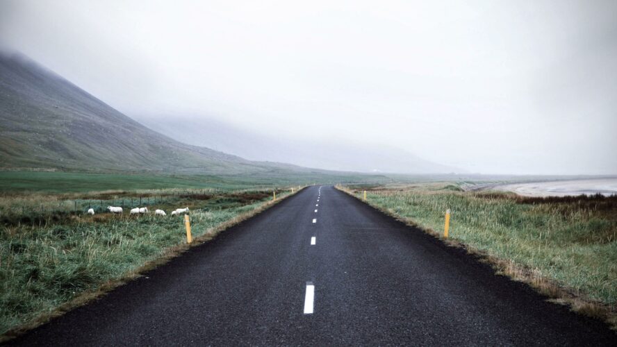 A road leading into mountains cloaked in mist.