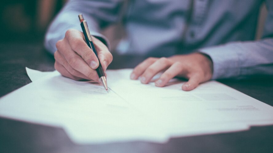 Letter being signed by man holding pen