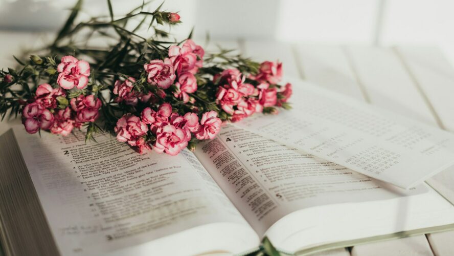 An open bible with a bouquet of pink flowers on top